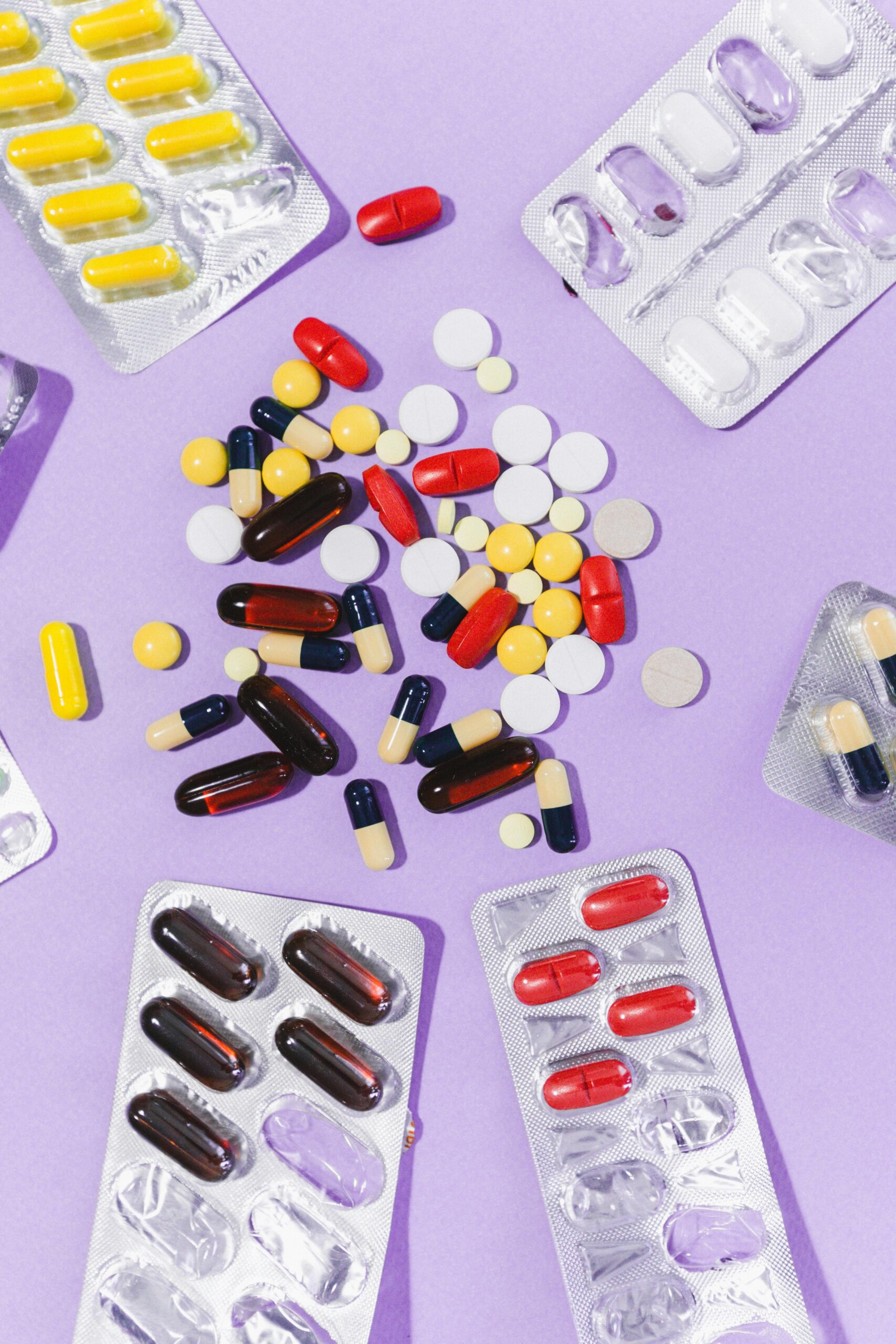 Close-up of various pills and capsules on a purple backdrop, showcasing pharmaceutical diversity.